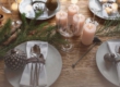 Table dressée de manière festive avec des bougies, des assiettes décorées et une décoration naturelle pendant l'Avent.