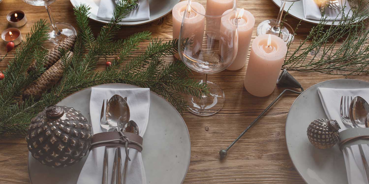 Festlich gedeckter Tisch mit Kerzen, geschmückten Tellern und Naturdeko im Advent.