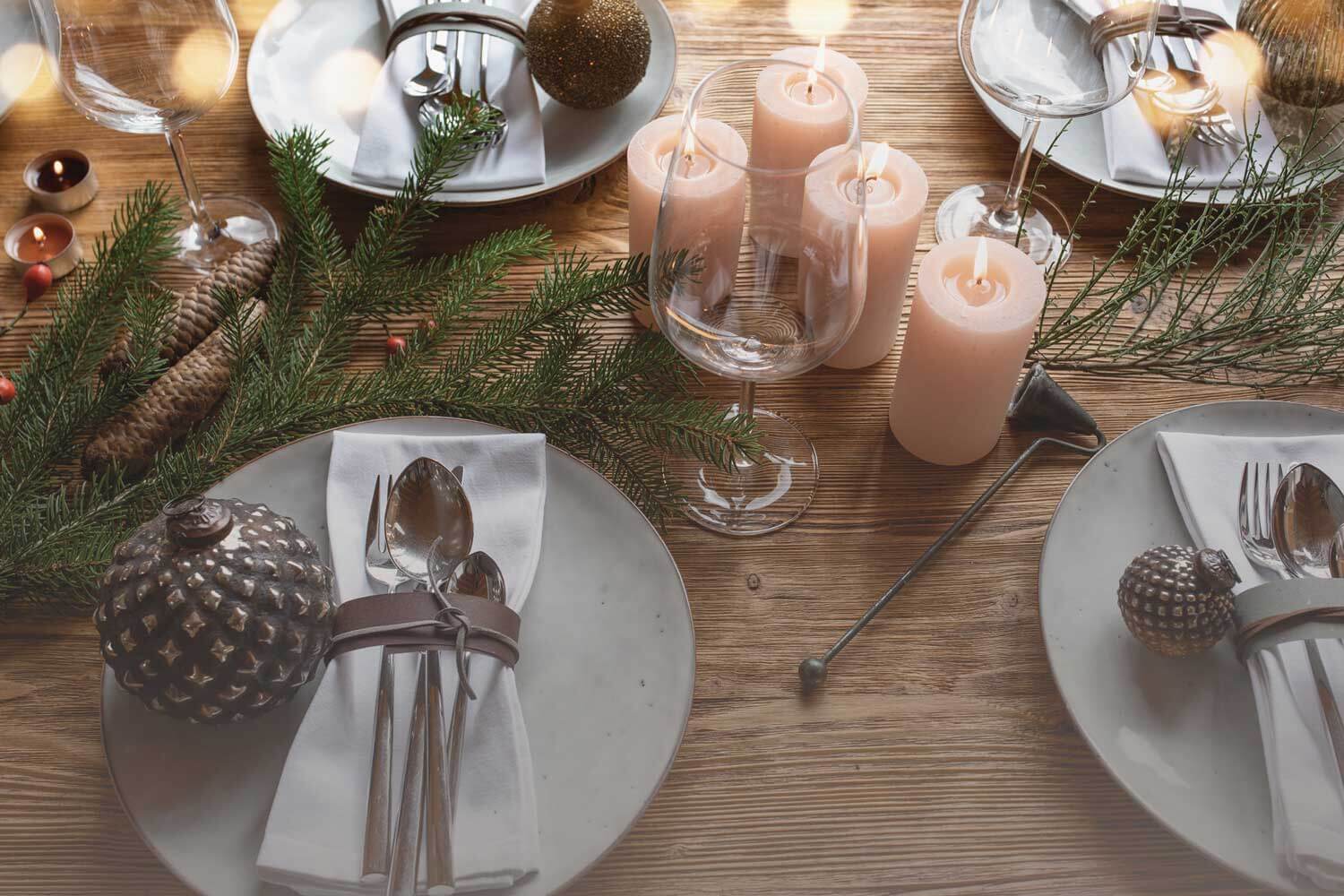 Festlich gedeckter Tisch mit Kerzen, geschmückten Tellern und Naturdeko im Advent.