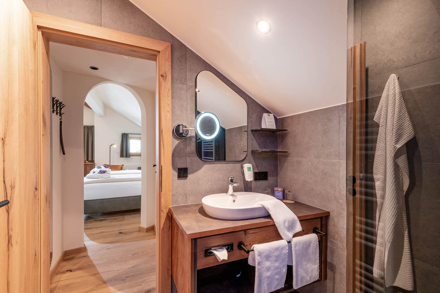 Modernes Badezimmer im Hotel Penzinghof mit Holzdetails und stilvollem Waschbecken.