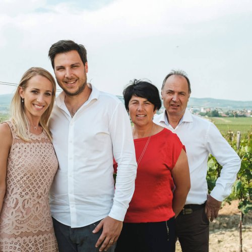 Winzerfamilie im Weinberg mit Blick auf die Hügel und Weinfelder in der Tiroler Landschaft.